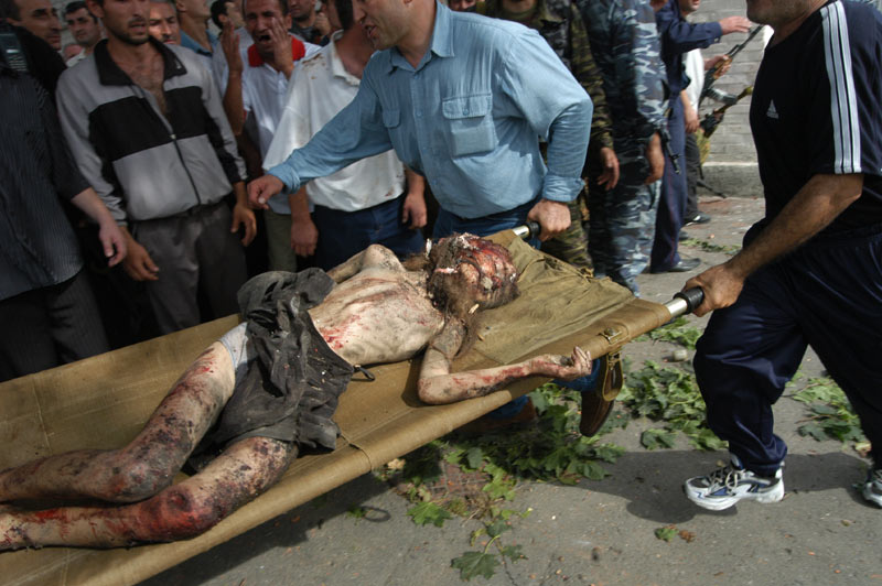 Men take out the wounded from the gym. Beslan