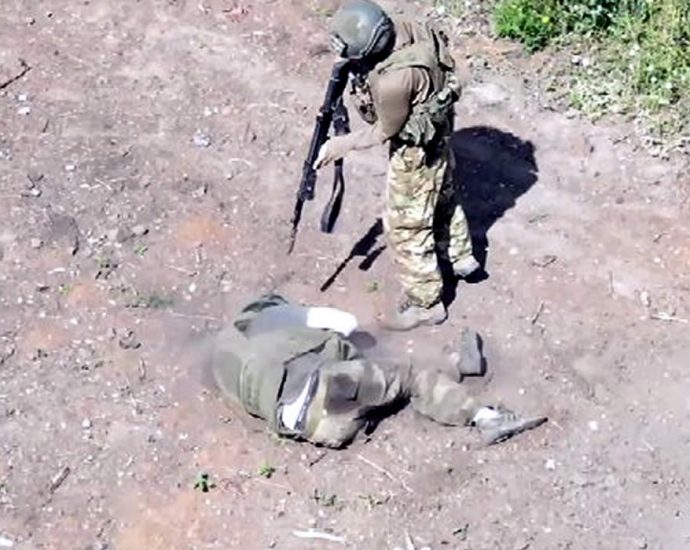 Русский военный добивает раненого солдата