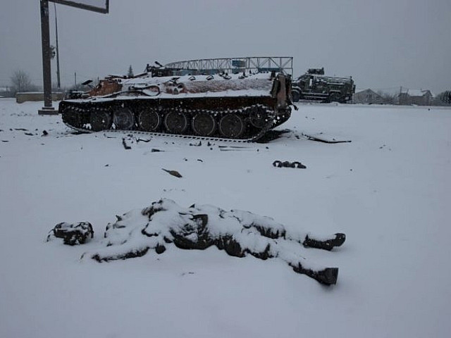 Труп бойца занесенный снегом на фоне брошенной военной техники. Украина