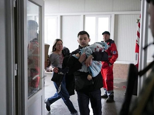 Мужчина несет раненого ребенка. Мариуполь. Украина