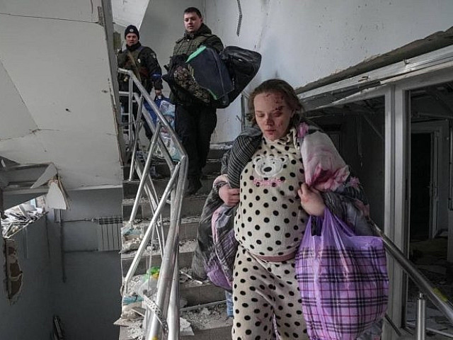 Беременная женщина спускается по лестнице из разрушенного родильного дома. Мариуполь