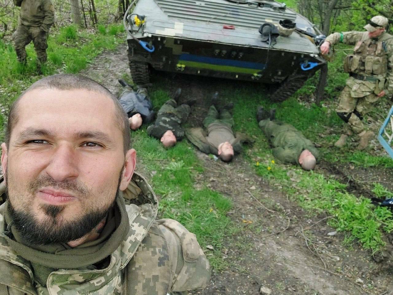 Украинский военный позирует на фоне трупов и БМП